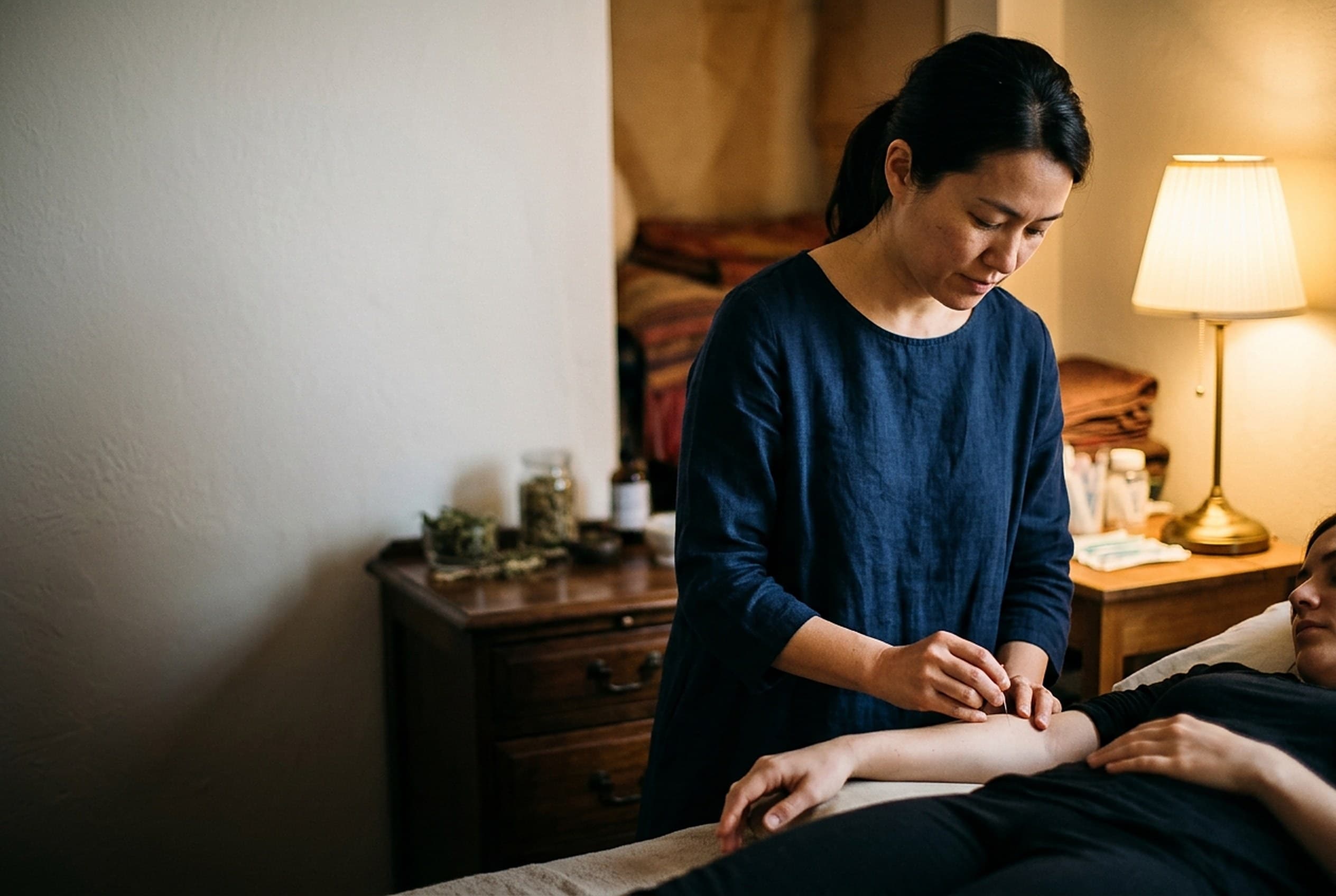 Acupuncturist placing a needle in a patient’s forearm